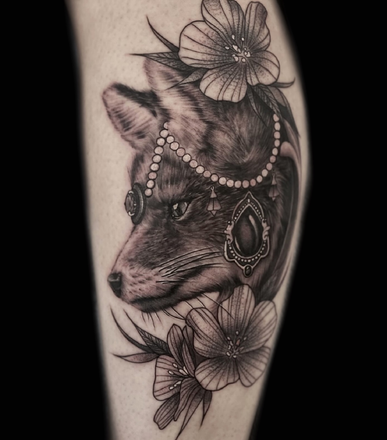 Black and grey fox tattoo framed with flowers and jewelry