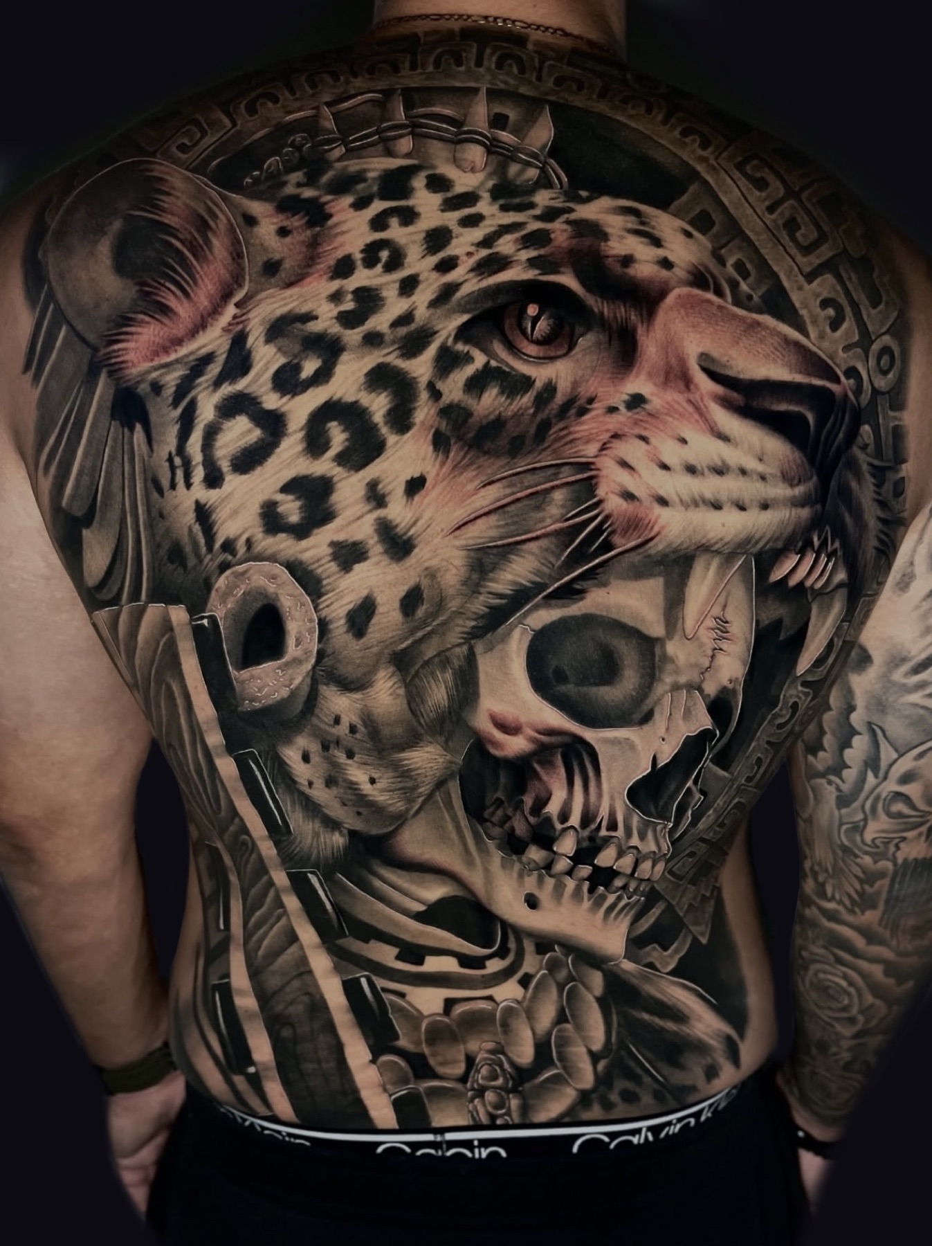 Large-scale jaguar and skull back tattoo by Josh Herrera