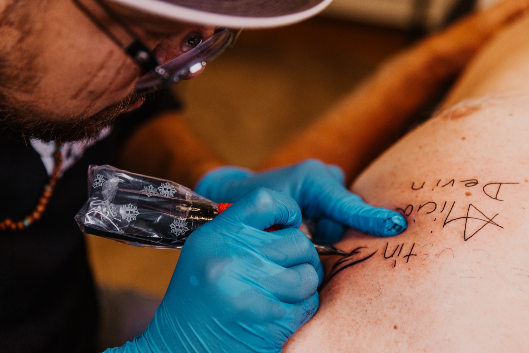 Josh Herrera tattooing hand-drawn lettering in the studio