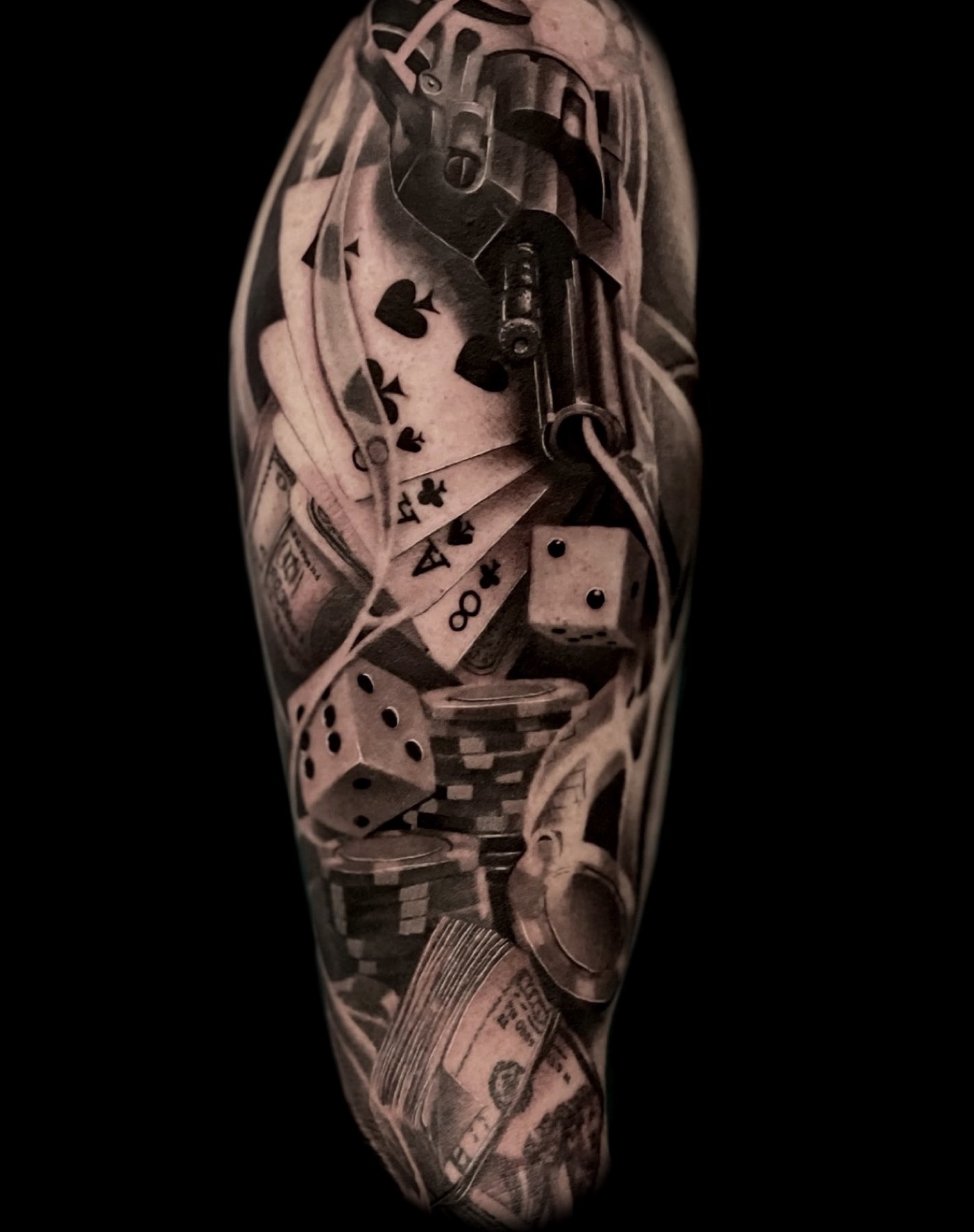 Las Vegas themed black and grey sleeve tattoo with cards, dice, and revolver